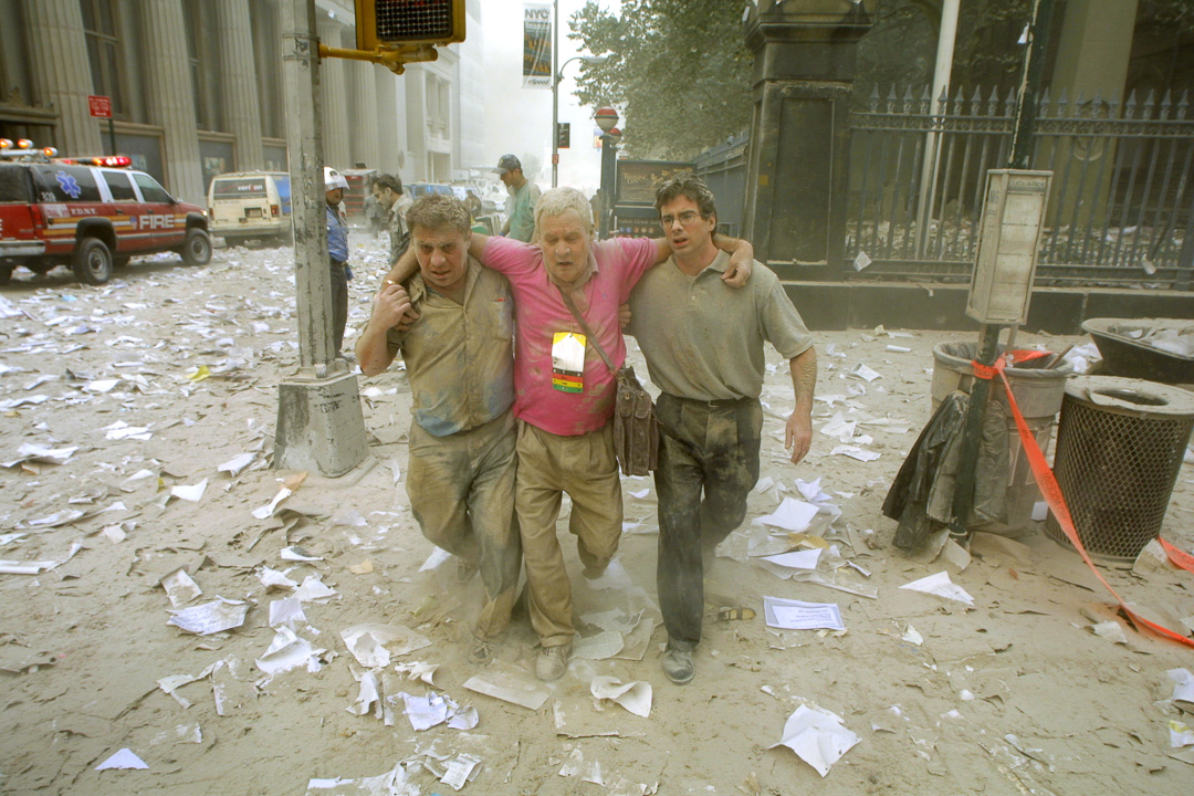 Two men help another after the first tower collapse.